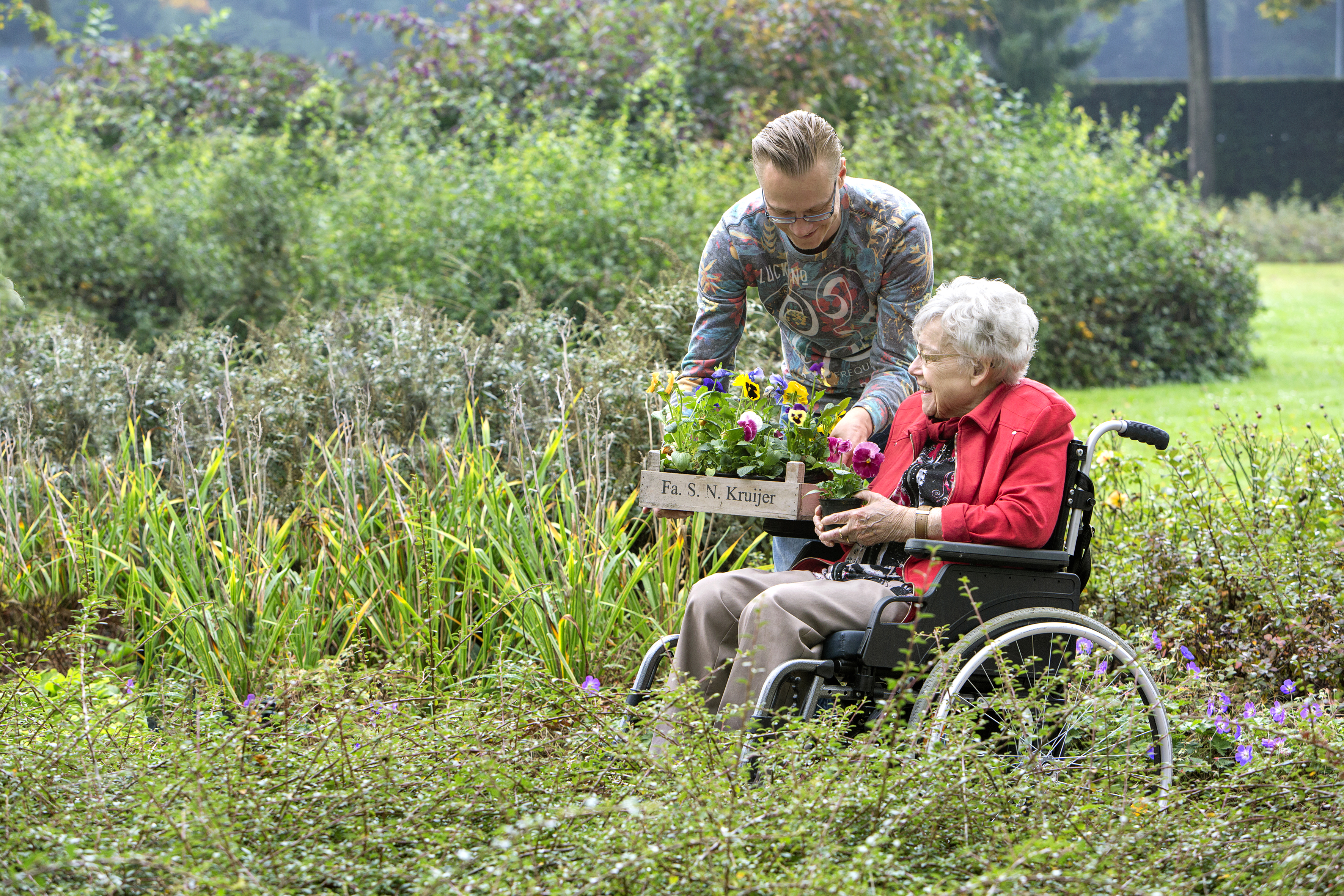 Man en vrouw plukken bloemen in tuin